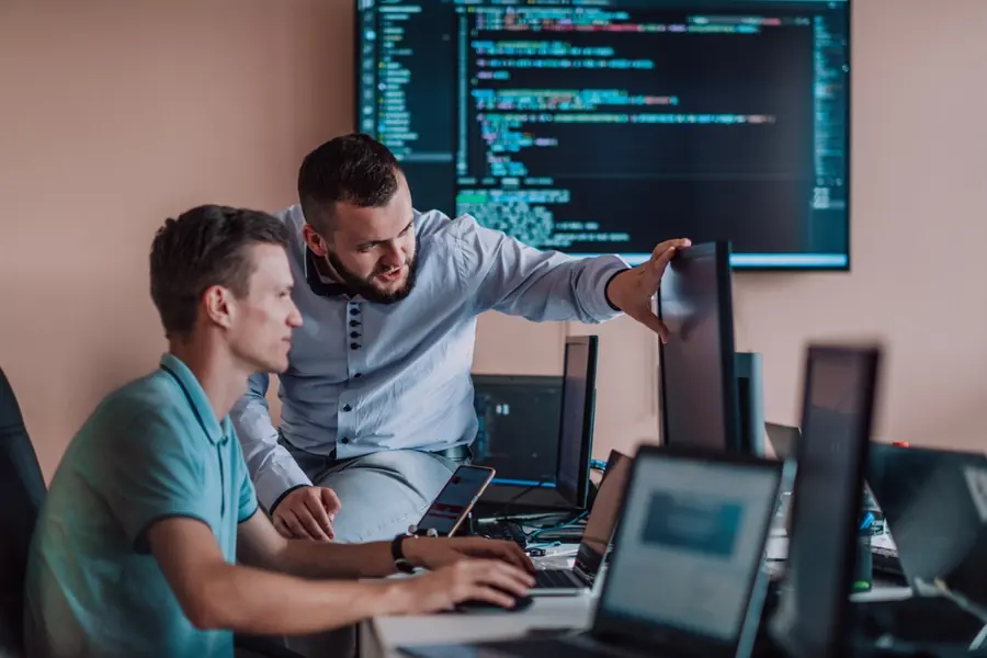 Two engineers working through a problem at a workstation
